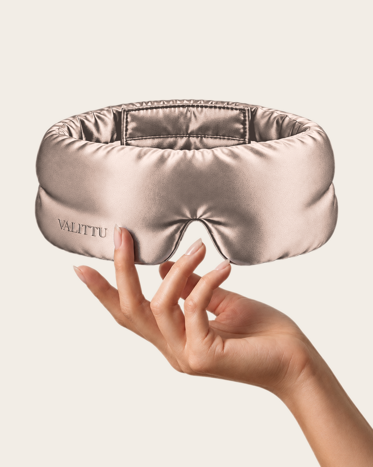 Hand holding the rose gold silk sleep mask