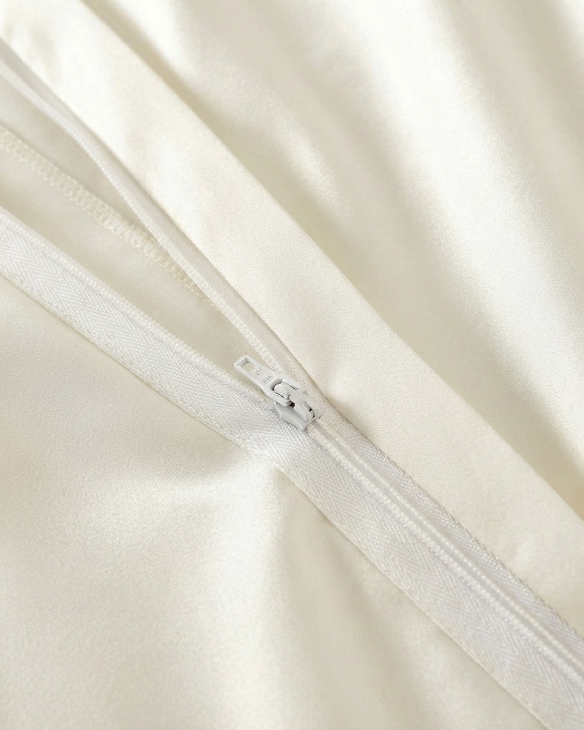 Close-up of a zip closure on ivory silk bedding