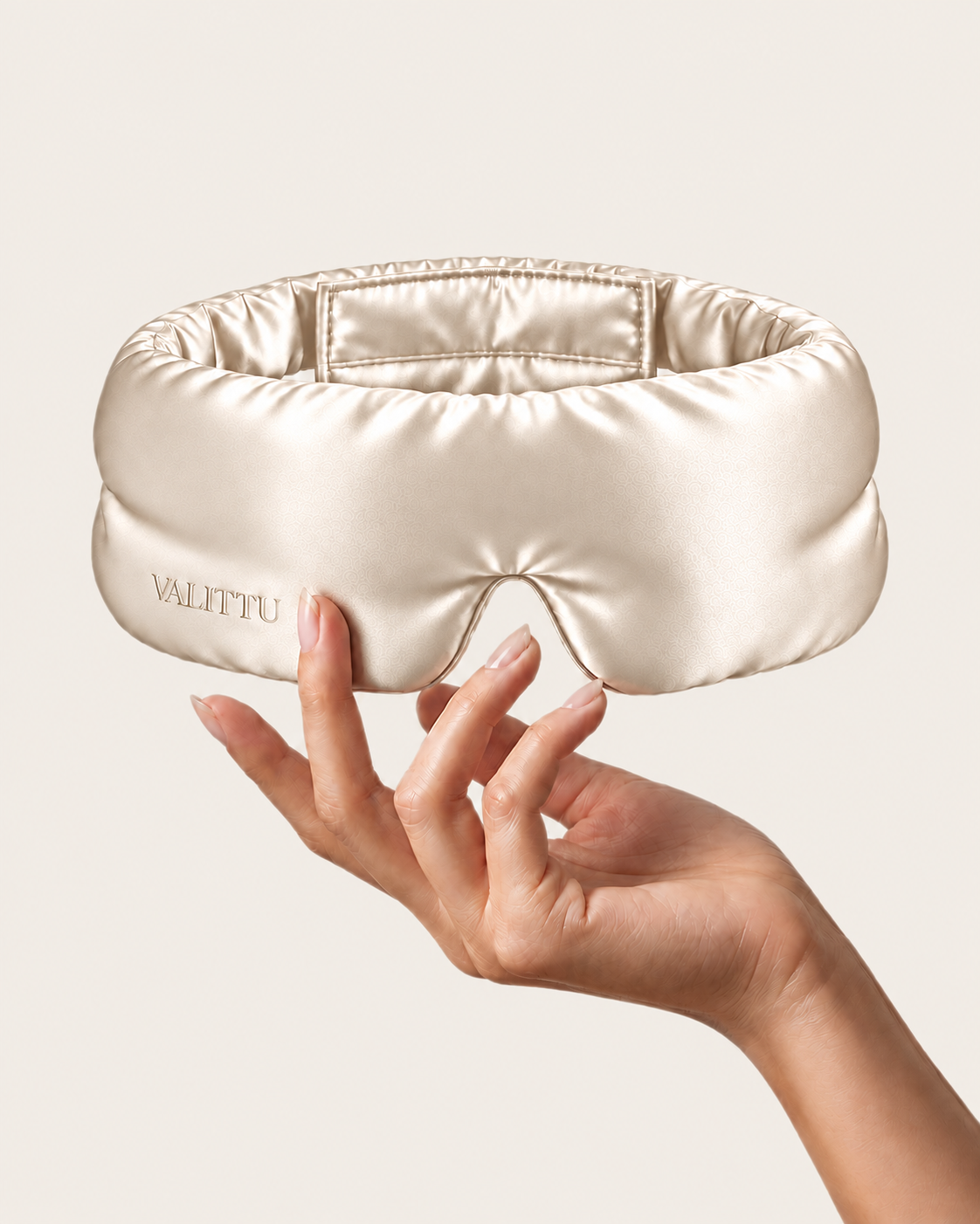 Hand holding the ivory silk sleep mask