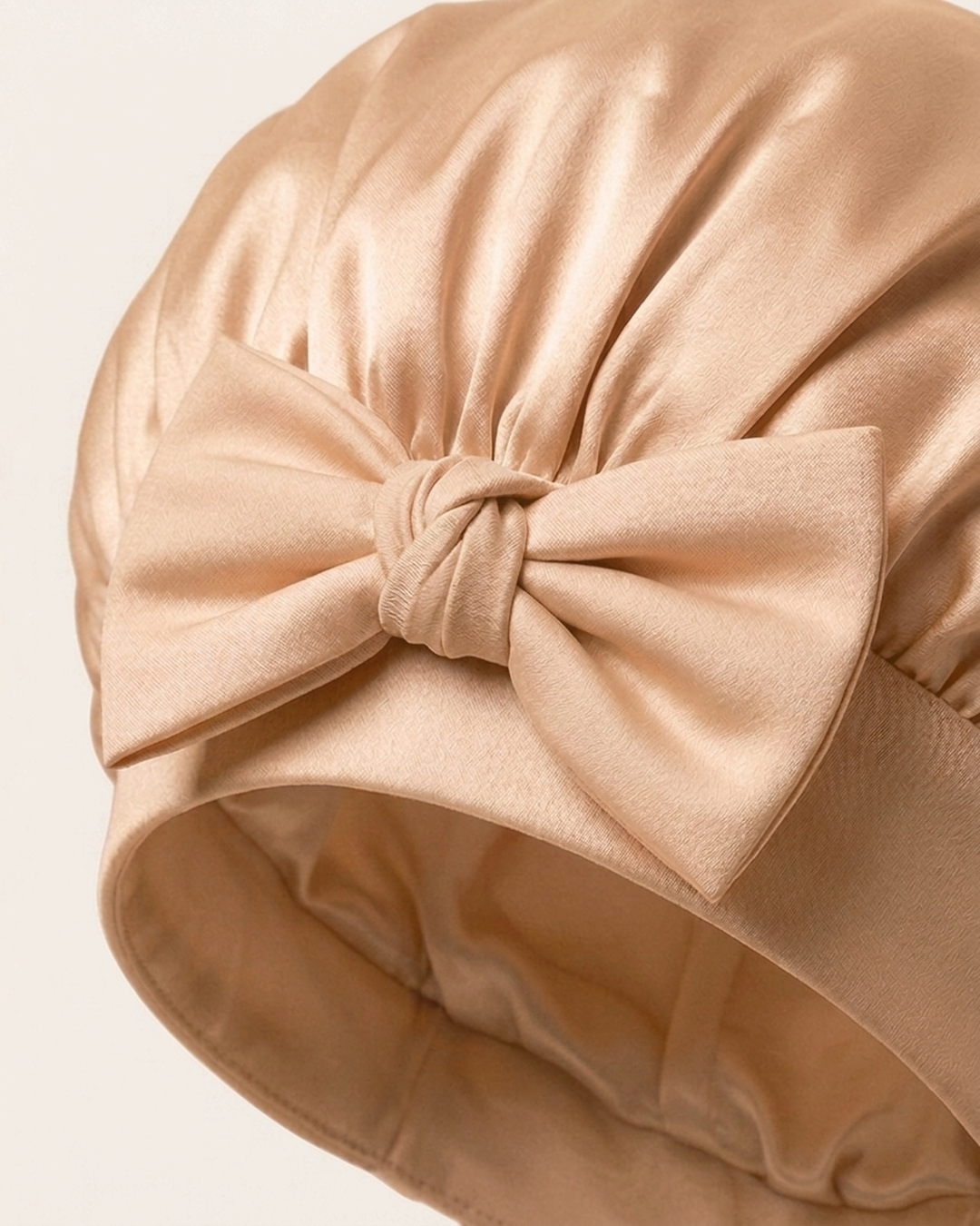 Close-up of the bow on the soft band of the rose gold silk bonnet