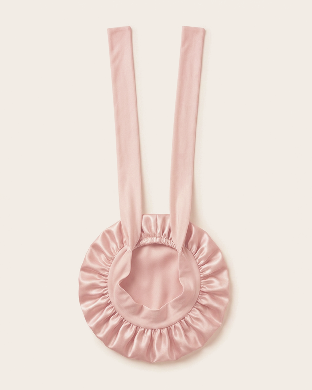 Pink silk bonnet laid flat with its ties extended