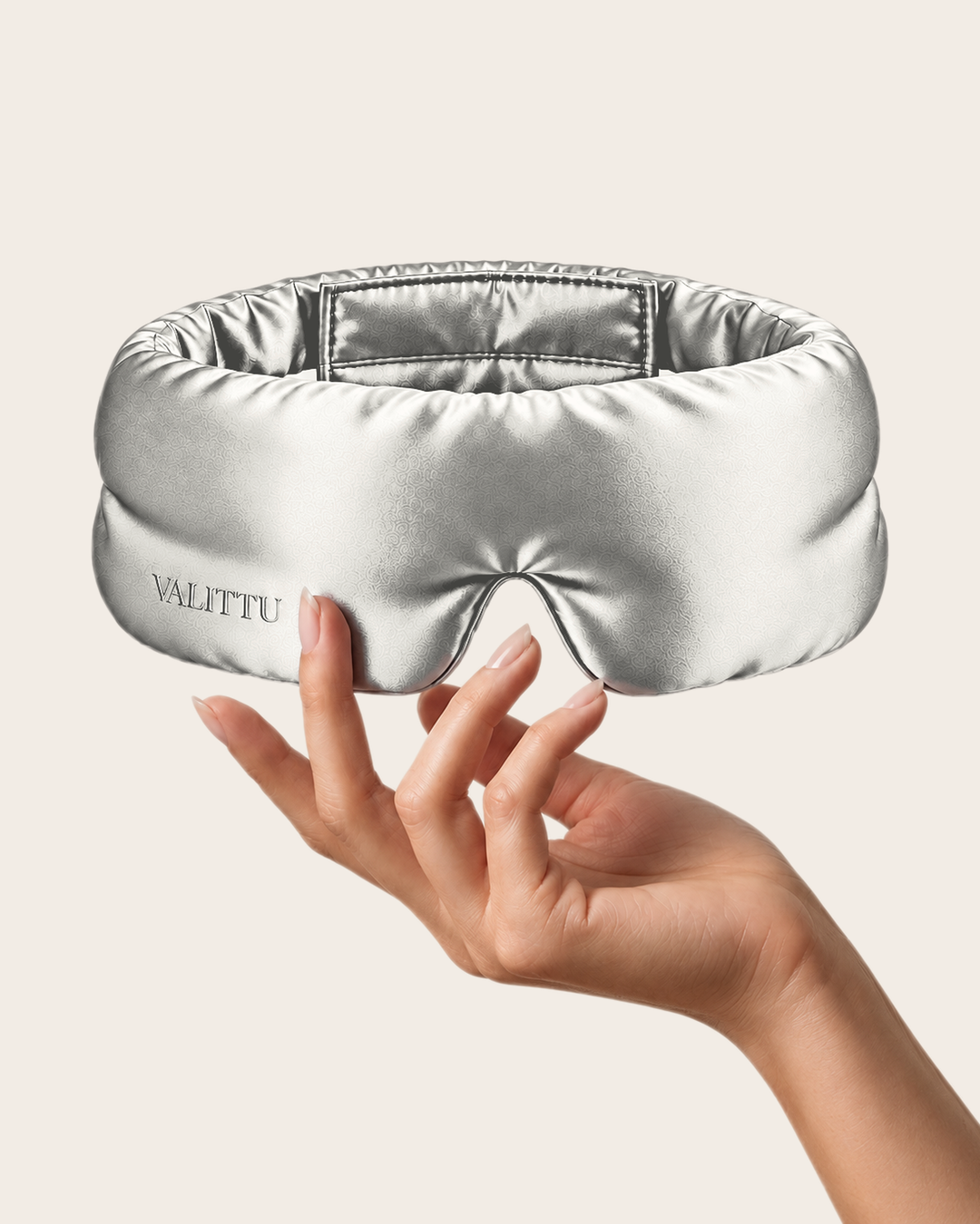 Hand holding the silver silk sleep mask